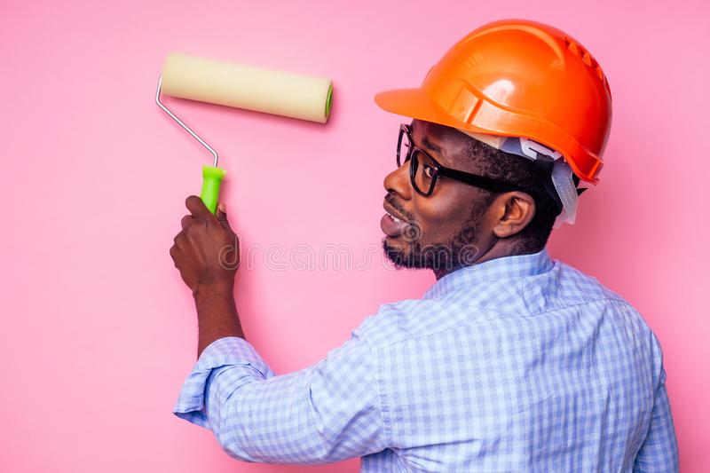 hombre-negro-africano-sosteniendo-rodillos-de-pintura-en-la-mano-pinta-pared-color-rosa-feliz-...jpg